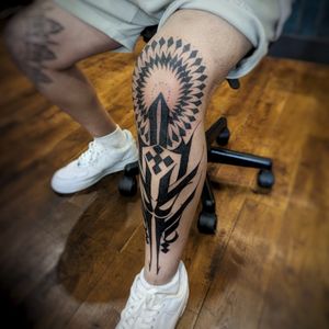 Experience the bold beauty of Chun Lee's blackwork tribal design on your knee. This intricate pattern will surely make a statement.