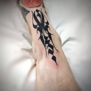 Bold blackwork design with intricate tribal pattern and inspiring quote for a unique foot tattoo by artist Chun Lee.
