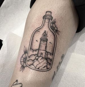 Intricate black and gray upper leg tattoo by Federico Colantoni featuring a stunning lighthouse and a mysterious message in a bottle.