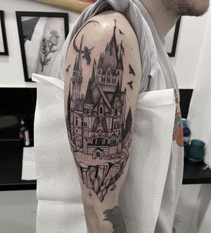 Impressively detailed blackwork castle tattoo on the upper arm, designed by Federico Colantoni. A bold statement of strength and power.