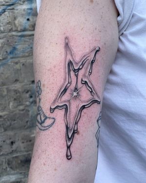 Elegant black and gray star tattoo on the upper arm, expertly done by Fresh Flower.