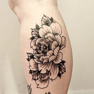 Vibrant neo-traditional lower leg tattoo featuring a unique blend of blooming flowers and skull by artist George Antony.
