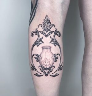 A stunning black and gray ornamental design featuring a delicate vase motif, expertly tattooed on the lower leg by Fresh Flower.