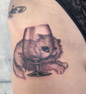 Elegant black and gray upper leg tattoo of a cat gracefully sitting inside a glass container, by Fresh Flower.