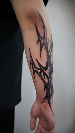 Get a bold blackwork pattern tattoo on your forearm by Jacky Yang for a timeless tribal look.