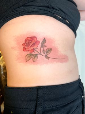 Adorn your ribs with a beautiful floral design by Kiky Flore featuring a stunning rose motif.