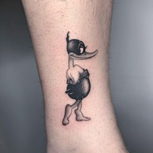 Get a cute black and gray duck tattoo on your lower leg by tattoo artist Fresh Flower. Perfect for anyone who loves cartoon animal tattoos!