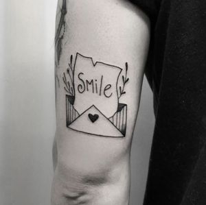 Elegant black and gray tattoo with fine line small lettering of a meaningful quote and envelope on upper arm by Elisa Thirteen.