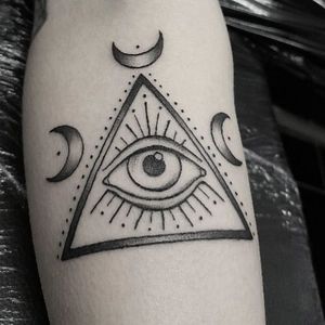 Elegant black and gray tattoo featuring a moon, triangle, and eye motif on the forearm, by Elisa Thirteen.