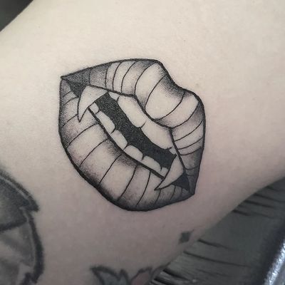 Embrace your dark side with a stunning black and gray vampire lips tattoo on your arm. Created by the talented artist Elisa Thirteen.