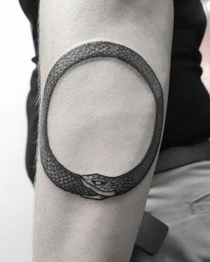 Stunning black and gray design on elbow by Elisa Thirteen, featuring a mesmerizing ouroboros snake twisting in a circle.