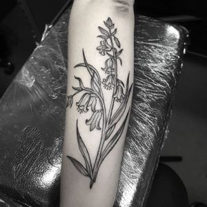 Elegant black and gray flower and plant design by Elisa Thirteen, perfectly placed on the forearm.