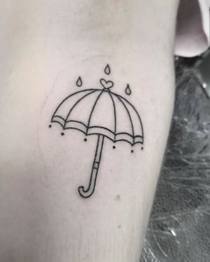 Elegant black and gray tattoo of an umbrella in the rain, beautifully rendered by tattoo artist Elisa Thirteen on the arm.
