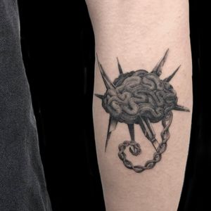 Stunning black and gray tattoo by Misa on forearm featuring intricate micro realism of a brain connected by a chain.