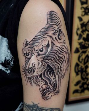 Bold and fierce tiger design on upper arm, expertly executed by tattoo artist Alex Travers.