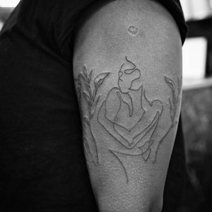 Experience the beauty of surrealism with this fine line tattoo featuring a man and woman on your upper arm. By Soheyl Astangi.