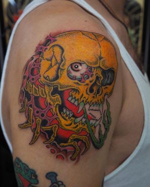 Get a bold new school skull tattoo on your upper arm by the talented artist Alex Travers. Stand out with vibrant colors and unique design.