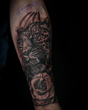 Experience the beauty of nature with this stunning black and gray tattoo featuring a realistic leopard and delicate rose on your lower leg. By tattoo artist Soheyl Astangi.