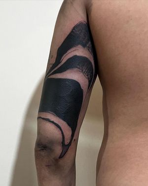 Experience the mesmerizing blend of blackwork and surrealism in this striking upper arm tattoo by Misa.