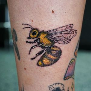 Get buzzed with this colorful new school bee tattoo by Soheyl Astangi on your lower leg.
