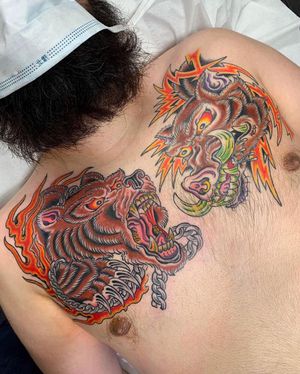 Bold neo-traditional chest tattoo featuring a bear and hog, expertly executed by Alex Travers.