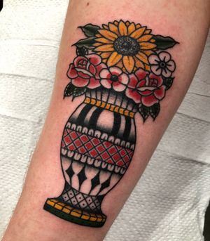 Capture the beauty of nature with this traditional upper-arm tattoo by Claudia Trash, featuring a vibrant sunflower and classic vase motif.