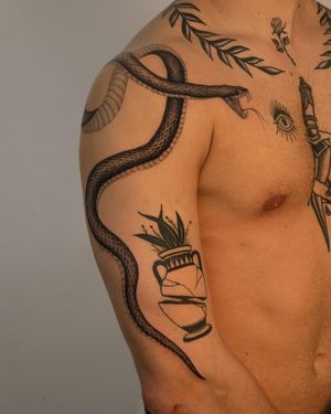 This striking black-and-gray snake tattoo by Federico Tronconi on the upper arm exudes a sense of power and mystique.
