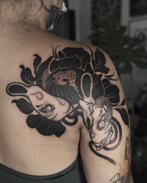 Admire Jacky Yang's stunning blackwork and neo-traditional design featuring a fox and delicate flower on your upper back.