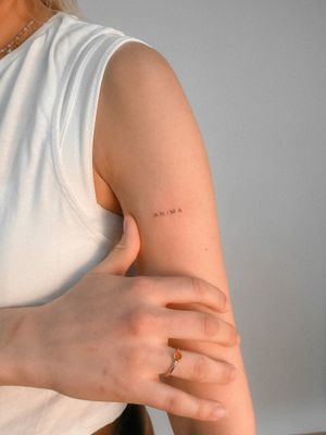 Get a sleek small lettering tattoo of your name on your upper arm by the talented artist Federico Tronconi. Perfect for a subtle and personal touch.