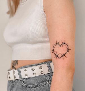 Embrace the beauty and pain with this black and gray heart wrapped in barbed wire, expertly done by Federico Tronconi on your arm.