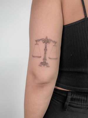 Achieve harmony with this elegant fine line balance motif on your upper arm by Federico Tronconi.