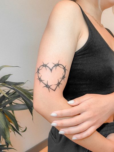 Black and gray tattoo featuring a heart entwined in barbwire by Federico Tronconi, perfect for your arm