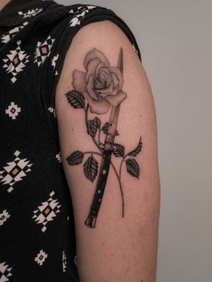 Elegant design by Federico Tronconi, featuring a delicate flower entwined with a sharp knife, bringing contrasting elements to life on your upper arm.