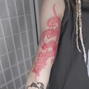 Get a stunning red ink Japanese-style dragon tattoo on your upper arm by renowned artist Jacky Yang. Fine line details bring this mythical creature to life.