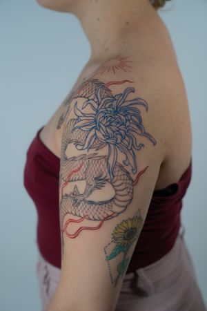 Discover the fierce beauty of a traditional Japanese dragon intertwined with delicate flowers, expertly inked by Federico Tronconi.