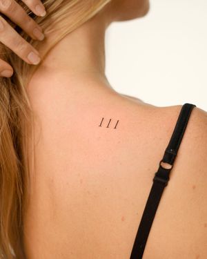 Get a sleek upper back tattoo with small lettering of your favorite number done by the talented artist Federico Tronconi.