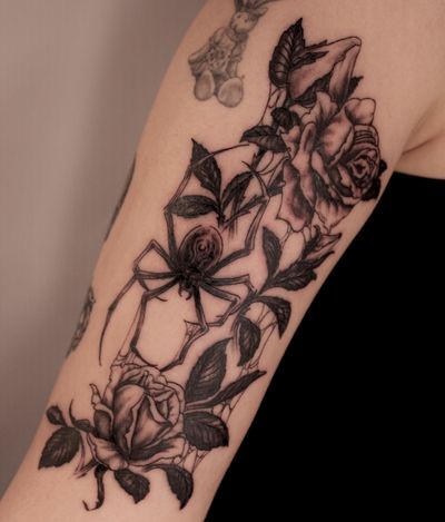 Traditional upper arm tattoo featuring a spider, flower, and rose, expertly done by José.