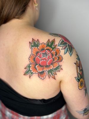 Stunning flower design on upper back by renowned artist Claudia Trash. Bold colors and intricate details make this tattoo a true masterpiece.
