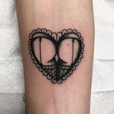Elegant black & gray design by Claudia Trash on the forearm, featuring a delicate heart and intricate booty motif.