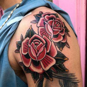 Get a timeless and bold traditional rose tattoo on your upper arm by the talented artist Claudia Trash. Stand out with this classic design.