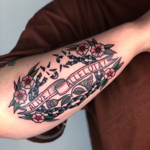Get inspired with this stunning traditional forearm tattoo featuring a beautiful flower and empowering quote by the talented artist Claudia Trash.