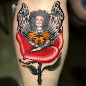 Get inked with this stunning traditional tattoo by Claudia Trash, featuring a beautiful design of a woman and flowers on your lower leg.