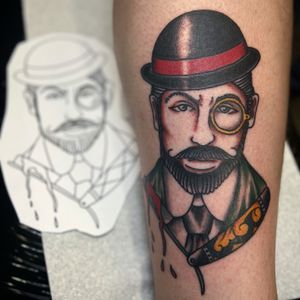Claudia Trash's stunning forearm tattoo featuring a man, razor blade, and cap in a unique neo-traditional style.