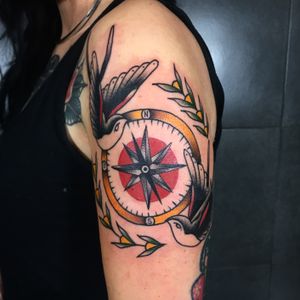Get a stunning traditional tattoo featuring a bird and compass design on your upper arm by the talented artist Claudia Trash.