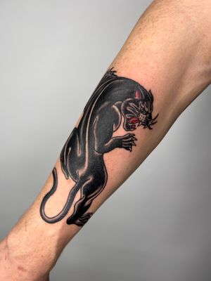 Bold and fierce traditional panther tattoo by Claudia Trash, perfectly placed on the forearm. Embrace your inner strength with this timeless design.