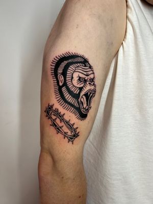 A striking traditional tattoo of a gorilla entwined with thorns, beautifully executed by Kayleigh Cole on the upper arm.