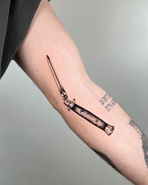 Get an edgy vibe with this knife tattoo by Joshua Williams, perfect for your arm in black and gray style.
