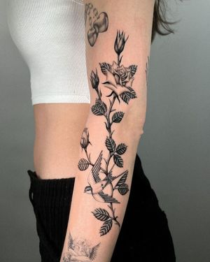 Elegant bird, tree, and flower motif beautifully rendered in black and grey on this mesmerizing sleeve tattoo.