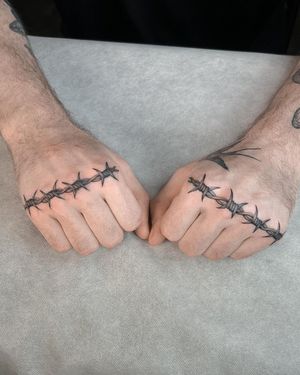 Get edgy with this bold and detailed black and gray barbed wire tattoo on your hand by talented artist Joshua Williams.