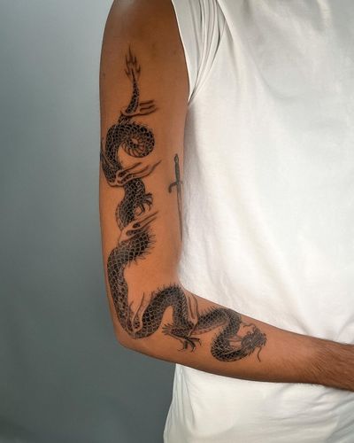 Experience the power and beauty of a Japanese black and gray dragon tattoo on your arm by artist Joshua Williams. Perfect for those seeking a bold and timeless design.
